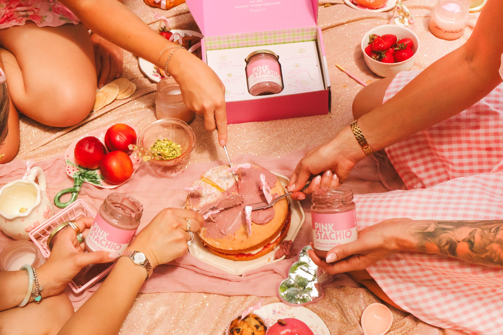 People enjoying a picnic with pinkstachio on a checkered blanket.